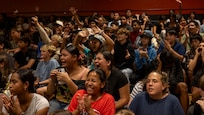 Students cheer from gymnasium stands.