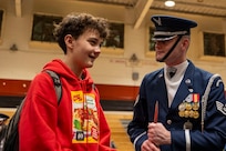 A student speaks with an Air Force Honor Guard Drill Team member in a gymnasium.