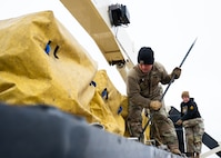 An Airman pries loose chain links holding replacement batteries for a launch facility.