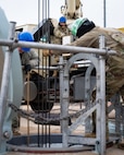 An Airman uses a crane to lower a replacement battery into a launch facility.