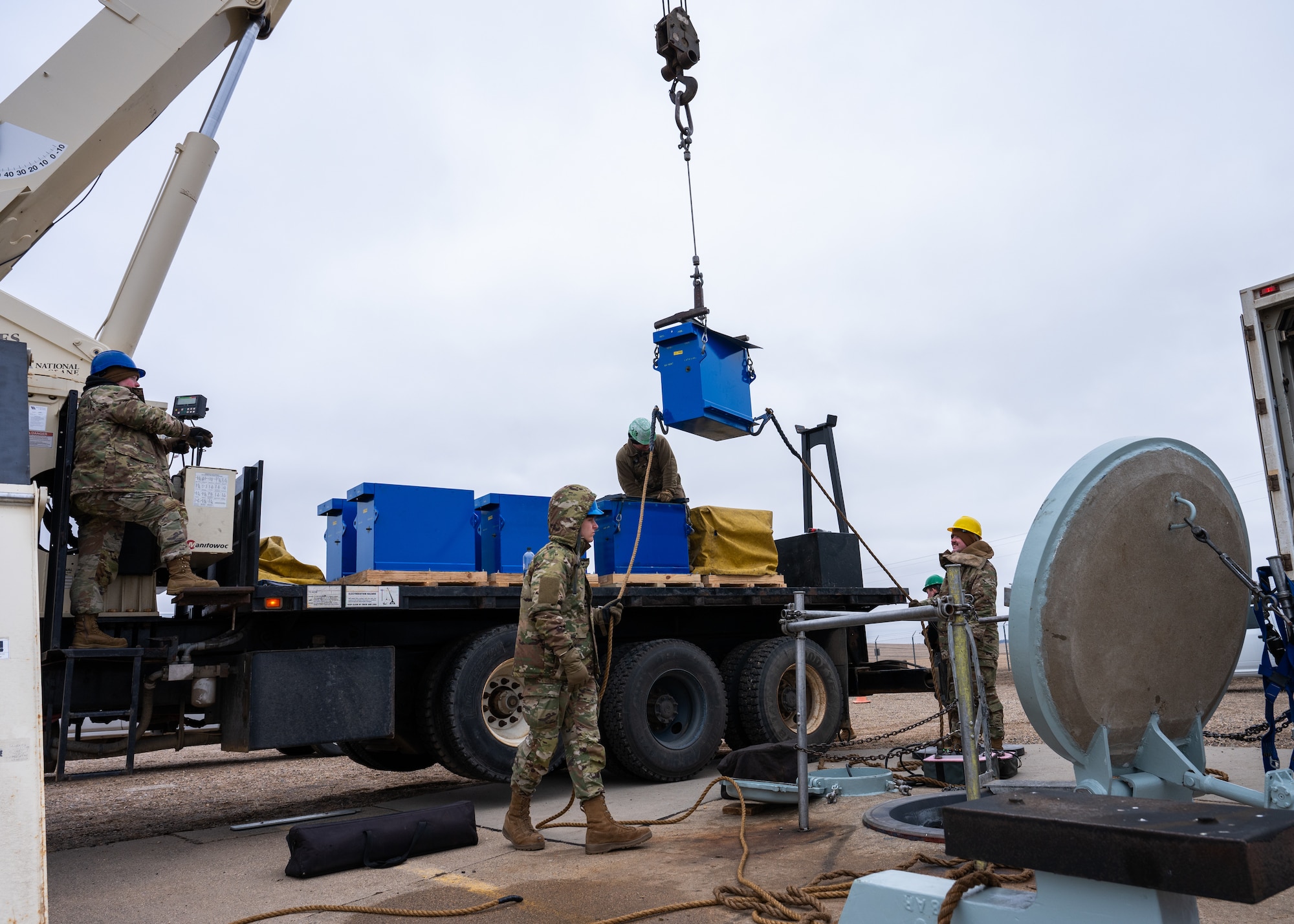 Airmen guide a replacement battery into a launch facility using a crane.