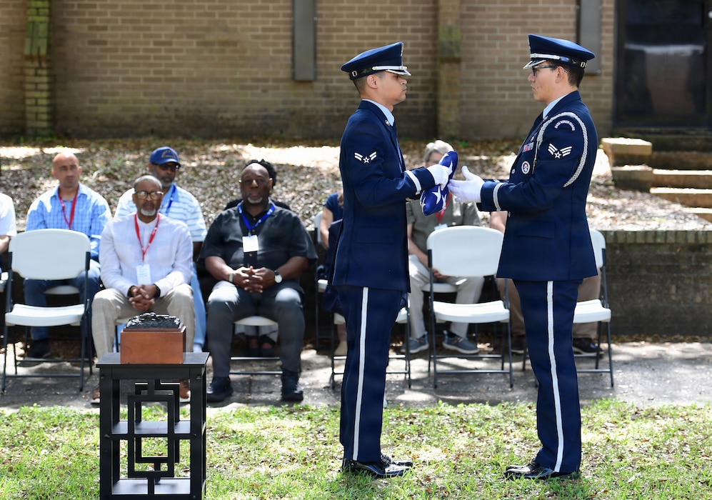 Two men in military uniforms fold a U.S. flag.