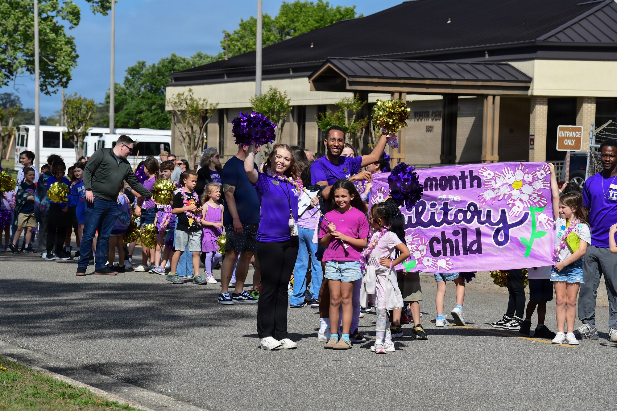 Children and staff hold a sign that say, Month of the military child during a walking parade.