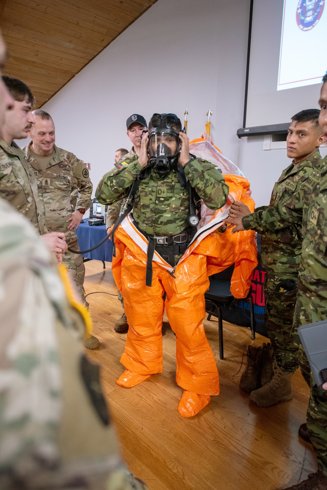 An Ecuadorian soldier dons a Kentucky National Guard Level A Ensemble, which protects emergency responders from unknown hazards, at the Kentucky Air National Guard base in Louisville, Ky., March 9, 2026. The Ecuadorians were visiting as part of the National Guard Bureau State Partnership Program to learn more about the Kentucky Guard’s emergency-response capabilities and interagency cooperation across the state, and to share their own techniques for responding to emergency contingencies. (U.S. Air National Guard photo by Phil Speck)