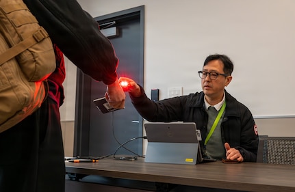 Joon Shik Nam, Eighth Army G35 Non-combatant Evacuation Operation (NEO) tracking system specialist, scans the credentials of a simulated evacuee assigned to U.S. Forces Korea during a simulated NEO during exercise Freedom Shield 26 at Yokota Air Base, Japan, March 10, 2026.