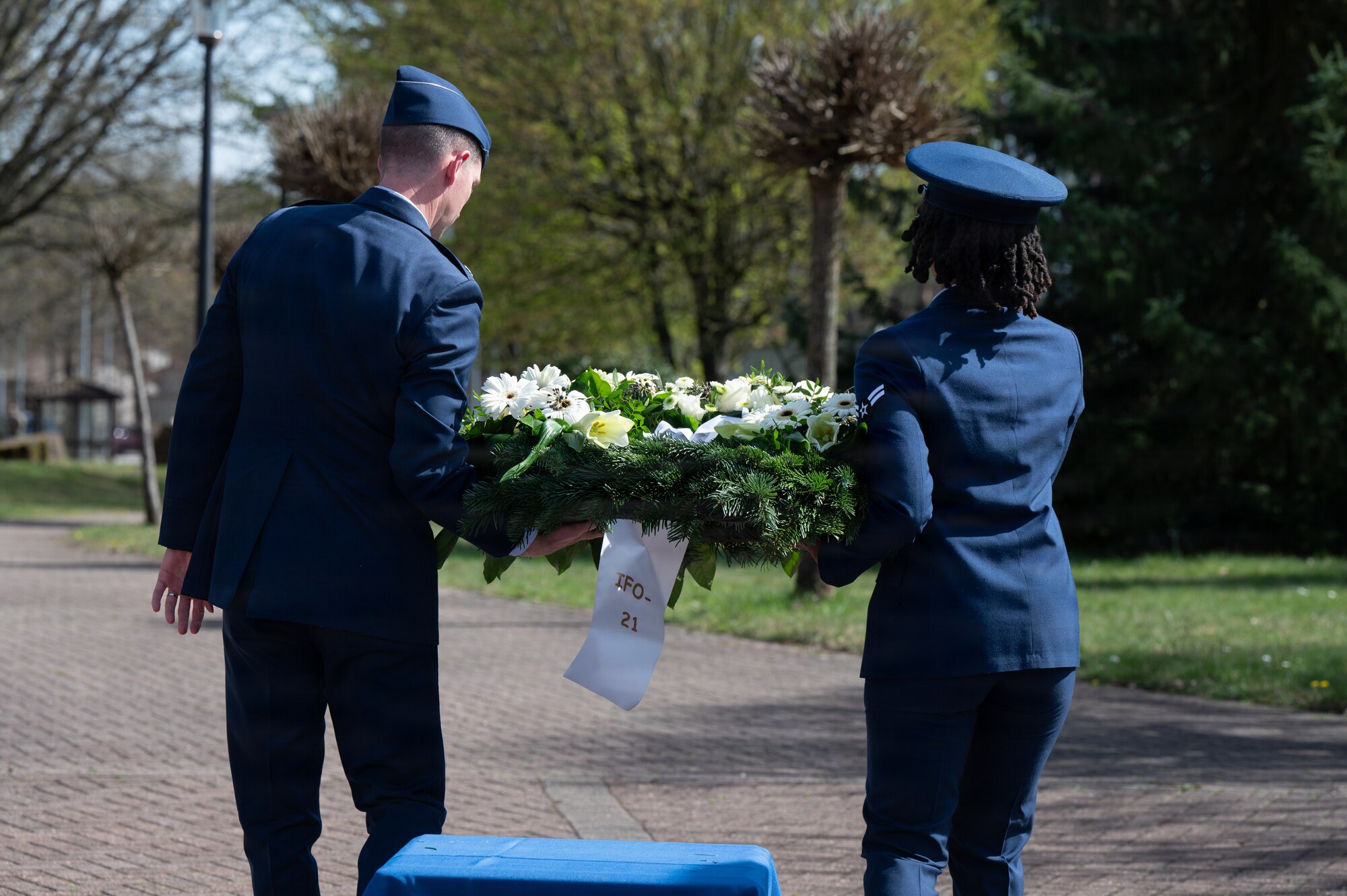 Two people carry a wreath for a memorial