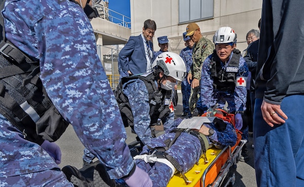 YOKOSUKA, Japan (March 11, 2026) — Japan Self-Defense Force (JSDF) medical personnel transport a simulated casualty on a stretcher during a bilateral mass casualty drill outside U.S. Naval Hospital Yokosuka. The training reinforced lifesaving interventions and teamwork in a dynamic operational setting. USNMRTC Yokosuka and JSDF Hospital Yokosuka conducted the drill to enhance joint medical response capabilities and lifesaving procedures in support of a free and open Indo-Pacific. (U.S. Navy photo by Daniel Taylor/USNMRTC Yokosuka Public Affairs)