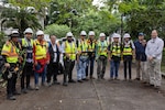 A group of workers with reflective vests and hard hats pose for a photo.