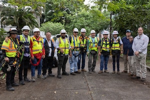A group of workers with reflective vests and hard hats pose for a photo.