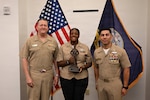 Rear Adm. Walter Brafford, left, commander, Naval Medical Forces Development Command (NMFDC), and Master Chief Hospital Corpsman Charles Padilla, NMFDC's acting command master chief, present Hospital Corpsman 1st Class Alisha Rogers, center, with a gift in recognition of her selection as the fiscal year 2025 region Senior Sailor of the Year. (U.S. Navy photo by Mass Communication Specialist 1st Class Shayla D. Hamilton)