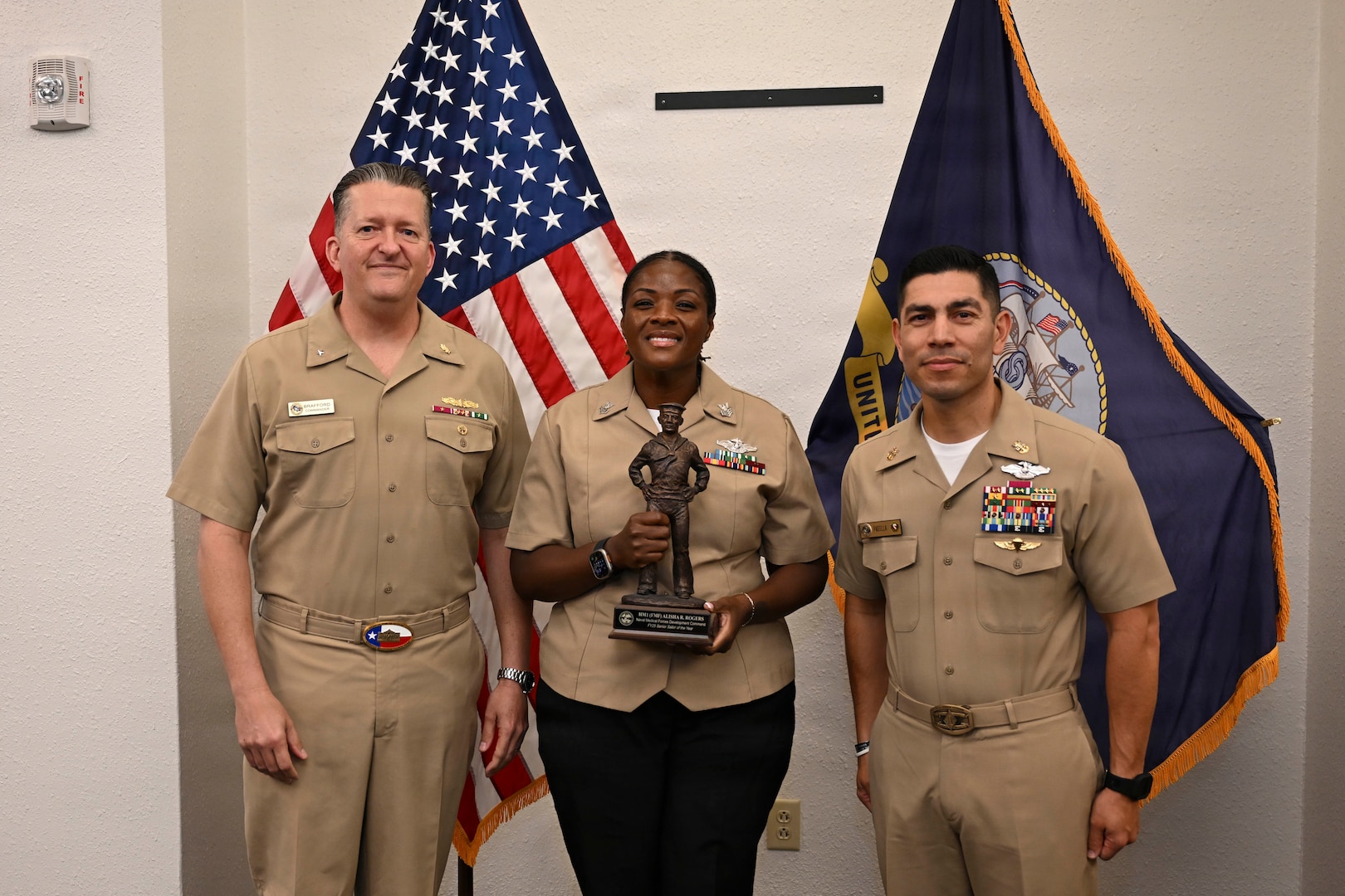 Rear Adm. Walter Brafford, left, commander, Naval Medical Forces Development Command (NMFDC), and Master Chief Hospital Corpsman Charles Padilla, NMFDC's acting command master chief, present Hospital Corpsman 1st Class Alisha Rogers, center, with a gift in recognition of her selection as the fiscal year 2025 region Senior Sailor of the Year. (U.S. Navy photo by Mass Communication Specialist 1st Class Shayla D. Hamilton)