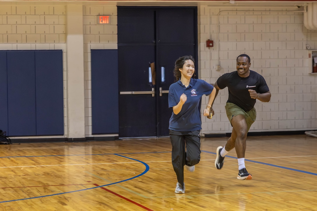 U.S. Marine Corps Staff Sgt. Burton, station commander of  Marine Recruiting Sub-station Fort Bend, Recruiting Station South Texas, races a student at Sharpstown High School during a USMC Fitness Challenge in Houston, Texas, Nov. 18, 2025. The USMC Fitness Challenge tests high school students’ physical endurance, strength, and teamwork while promoting discipline, resilience, and mental toughness through exercises modeled after Marine Corps training. (U.S. Marine Corps photo by Cpl. Christian Salazar)