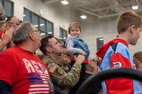 A Nebraska Army National Guard Soldier assigned to the 67th Maneuver Enhancement Brigade holds his child during a send-off ceremony at Lincoln Northwest High School in Lincoln, Nebraska, April 11, 2026.
