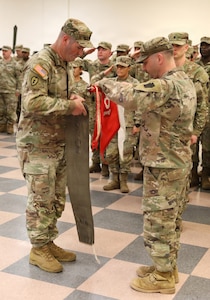 U.S. Army 1st Sgt. Brandon Lutz, with Troop D, 2nd Squadron, 104th Cavalry Regiment, 56th Mobile Brigade Combat Team, 28th Infantry Division, retires the troop guidon with the assistance of Capt. Robert Tomlinson III during the 2-104 Cav deactivation ceremony on Fort Indiantown Gap, Pennsylvania, March 21, 2026.