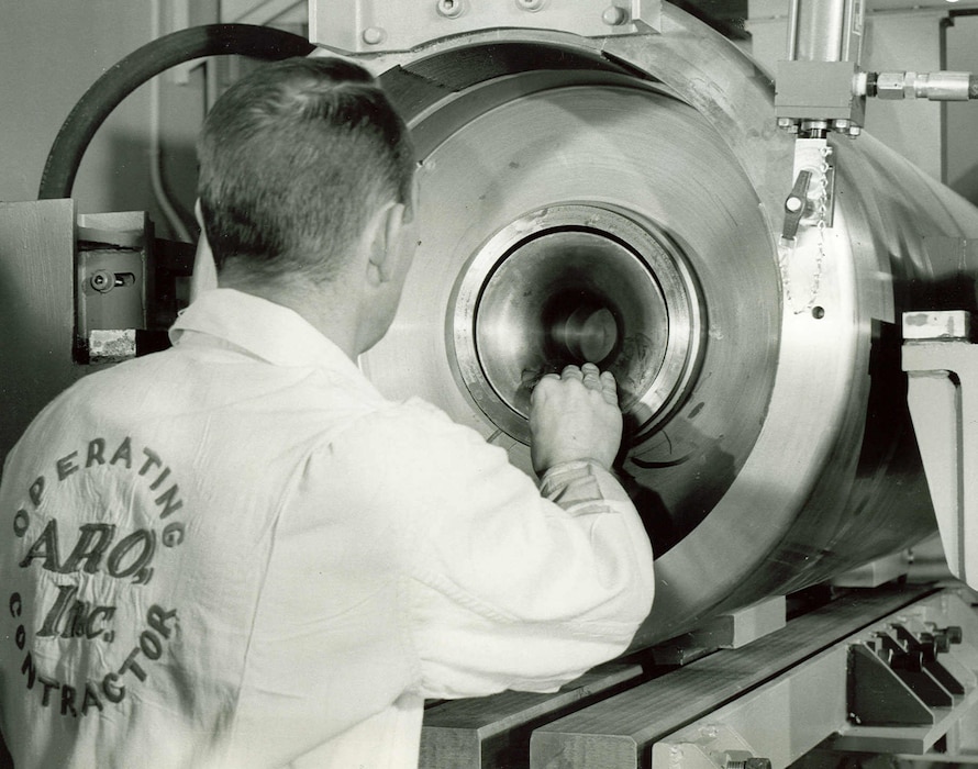 An Arnold Research Organization technician inserts a projectile encased in a launching sabot into the Range G High Impact Ballistic Testing Facility at Arnold Engineering Development Center in 1963. ARO was the first company awarded a contract to operate AEDC. The contract between ARO and the Air Force was signed June 29, 1950. (U.S. Air Force photo)