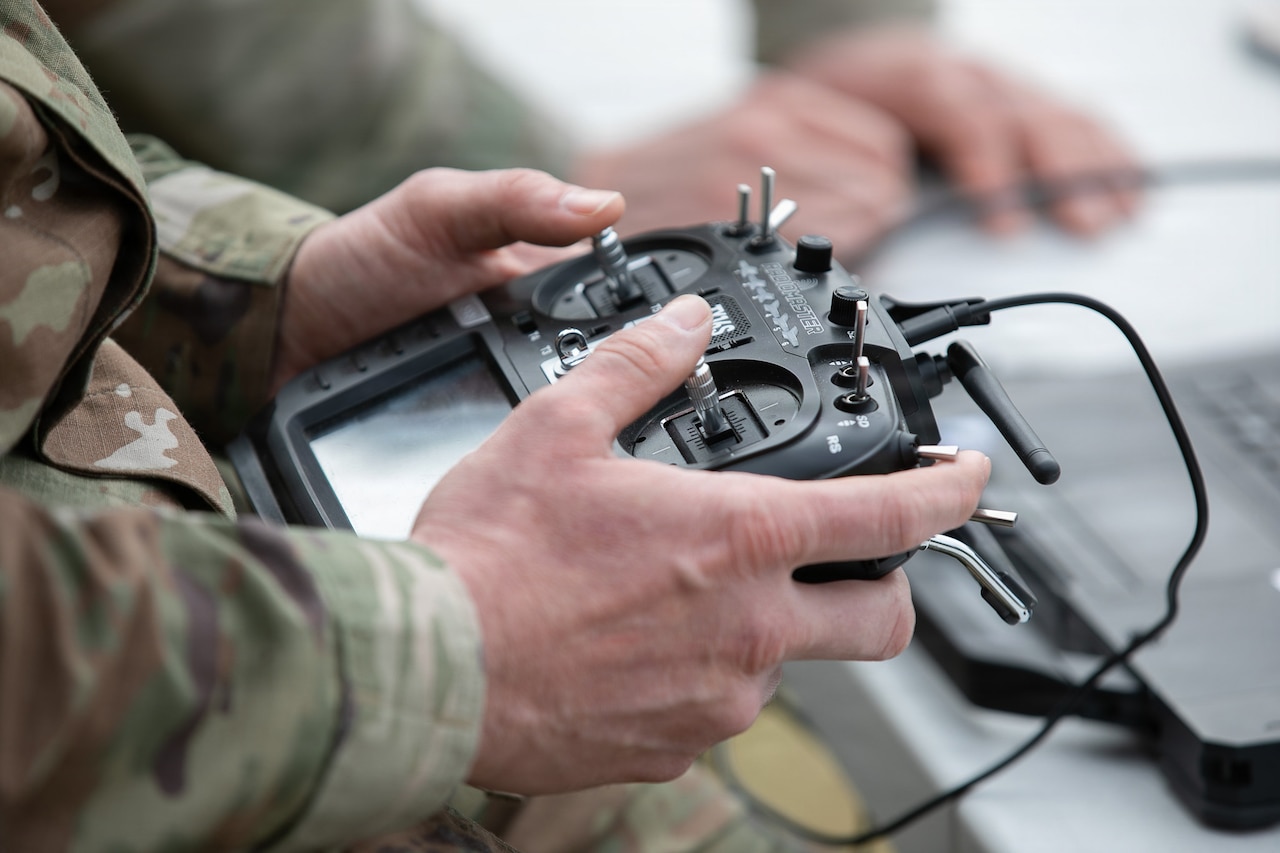A close-up view of hands holding a remote control used to pilot a drone.