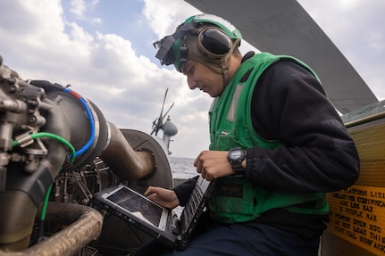 Aviation Electrician's Mate 2nd Class Benjamin Reyes, from San Diego, assigned to Helicopter Maritime Strike Squadron (HSM) 51, references a technical manual during an engine maintenance check of an MH-60R Sea Hawk on the flight deck of the Arleigh Burke-class guided-missile destroyer USS Preble (DDG 88) in the East China Sea, Jan. 29.  (U.S. Navy photo by Mass Communication Specialist 1st Class Ryre Arciaga)