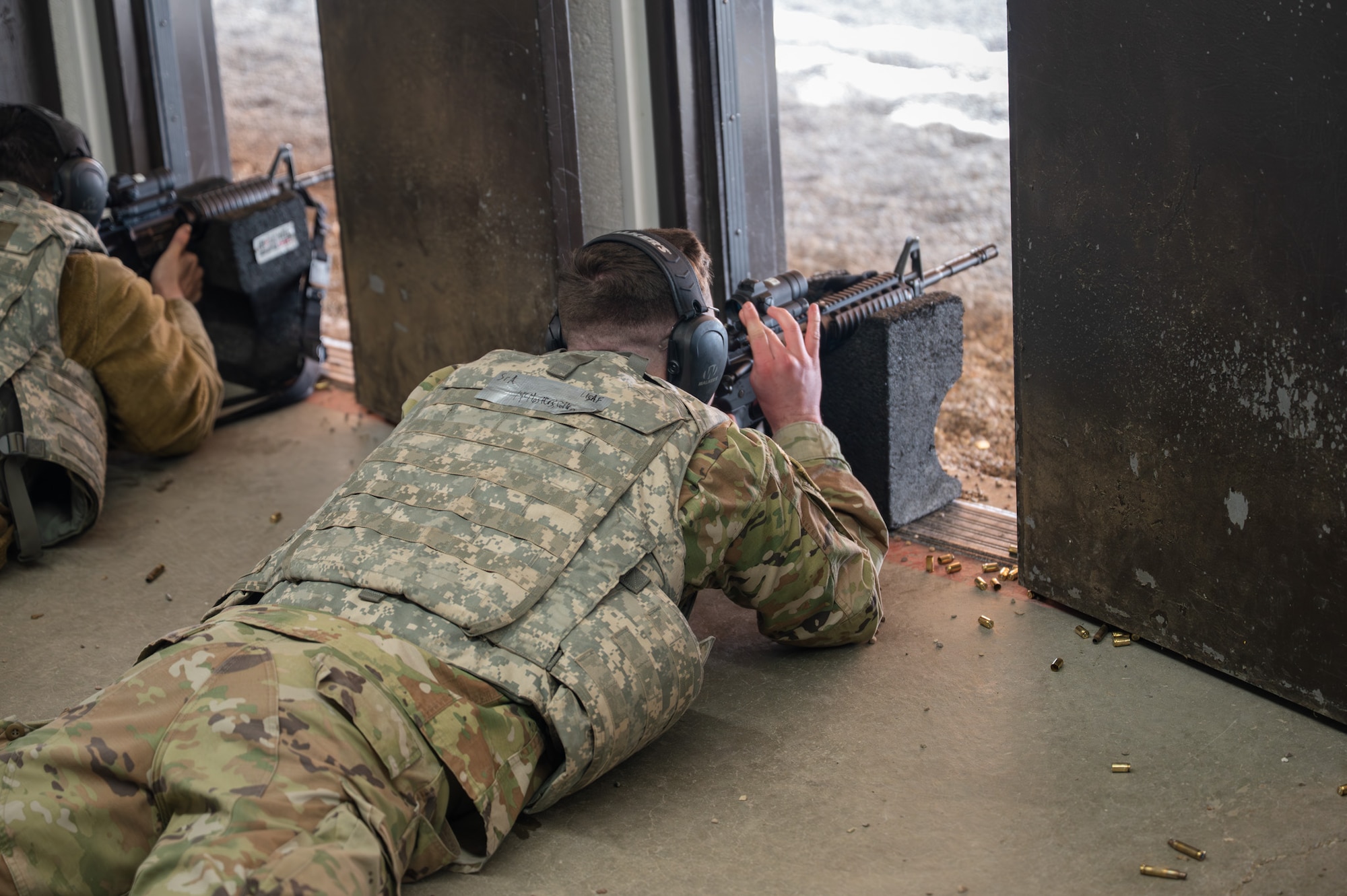 A uniformed man aims a firearm at a target.