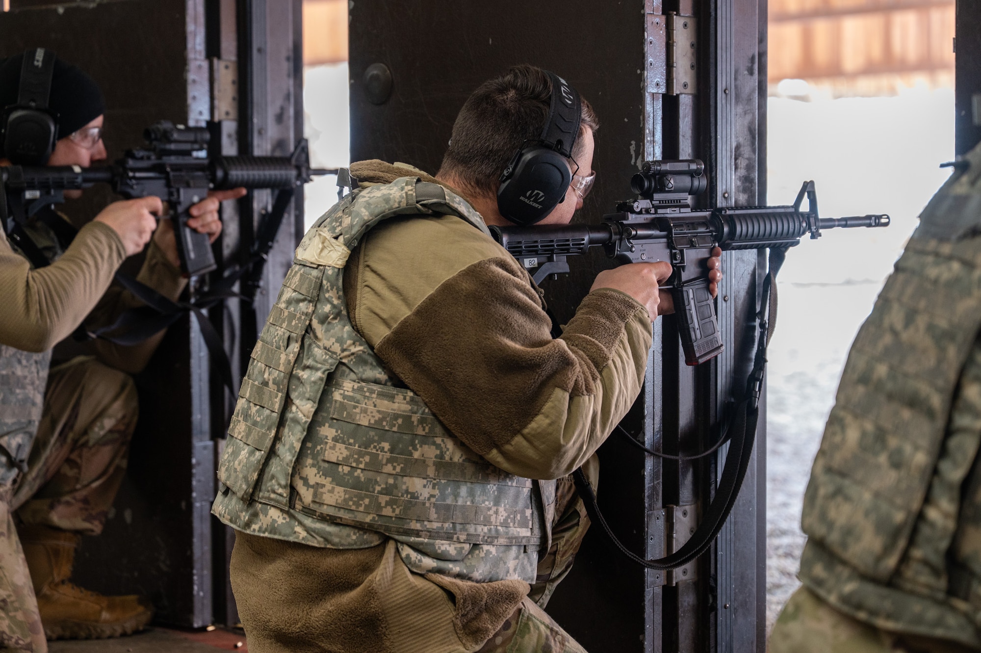 A uniformed man aims a firing arm at a target.