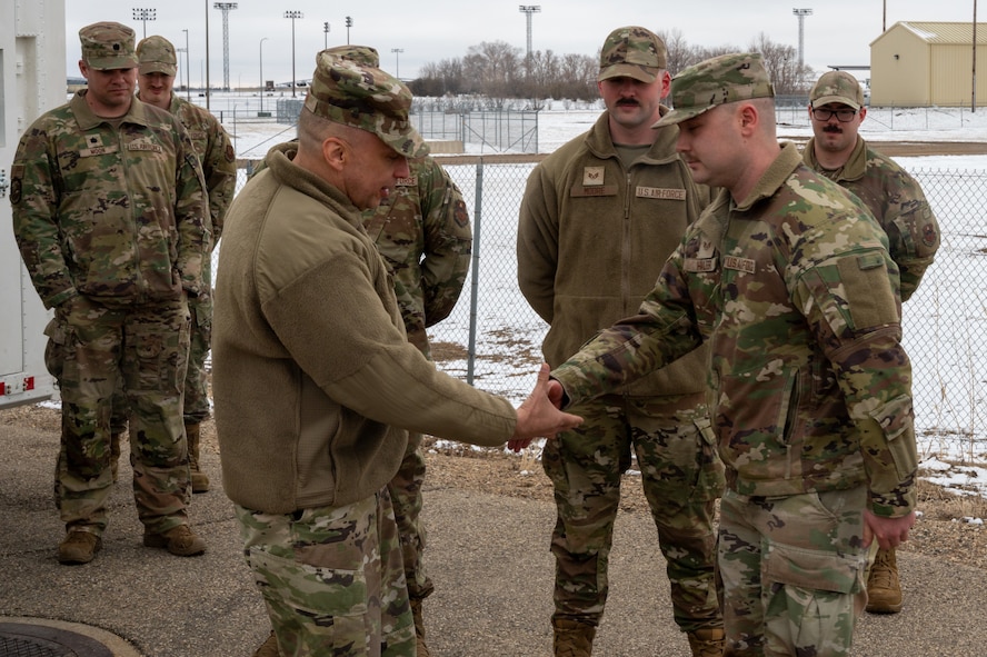 U.S. Air Force Maj. Gen. Lyle Drew, director Defense Threat Reduction Agency (DTRA), coins U.S. Air Force Staff Sgt. Caleb Haler, assigned to the 373rd Training Readiness Squadron Detachment 23 at Minot Air Force Base, North Dakota, March 30, 2026. DTRA is a combat support agency within the U.S. Department of Defense focused on countering and deterring weapons of mass destruction.