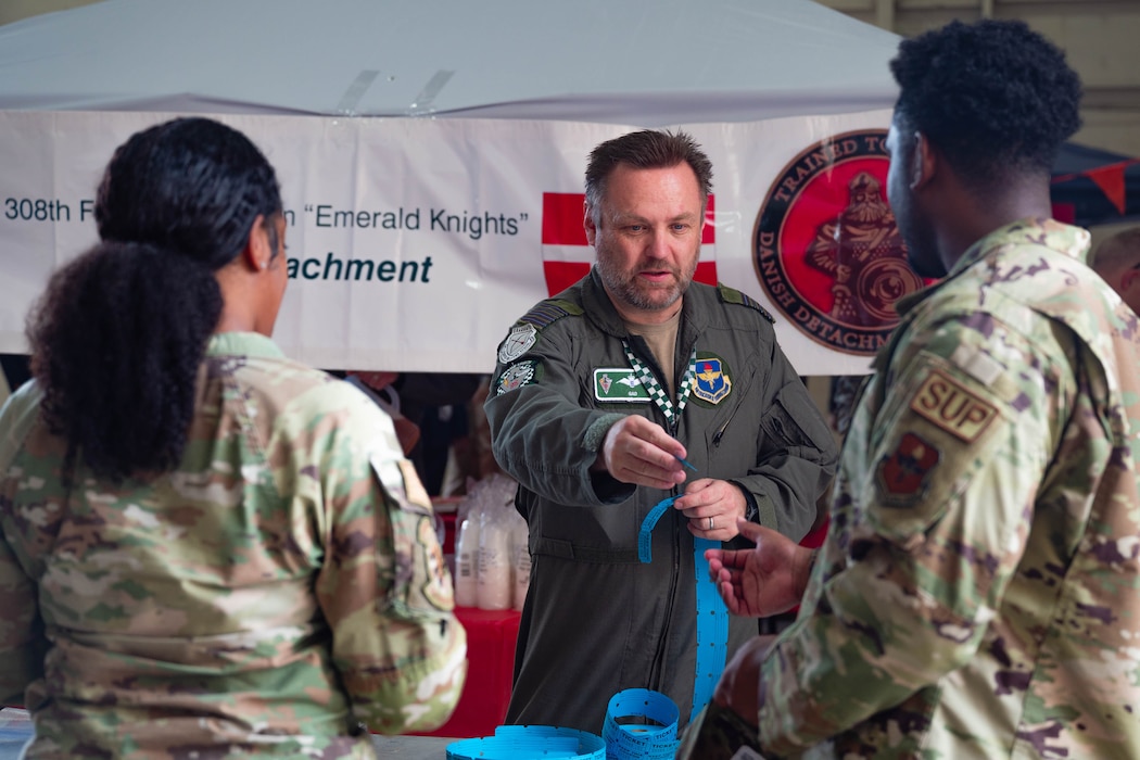 U.S. Air Force Airmen assigned to the 56th Fighter Wing receive raffle tickets from a Belgian pilot during International Day 2026, April 10, 2026, at Luke Air Force Base, Arizona.