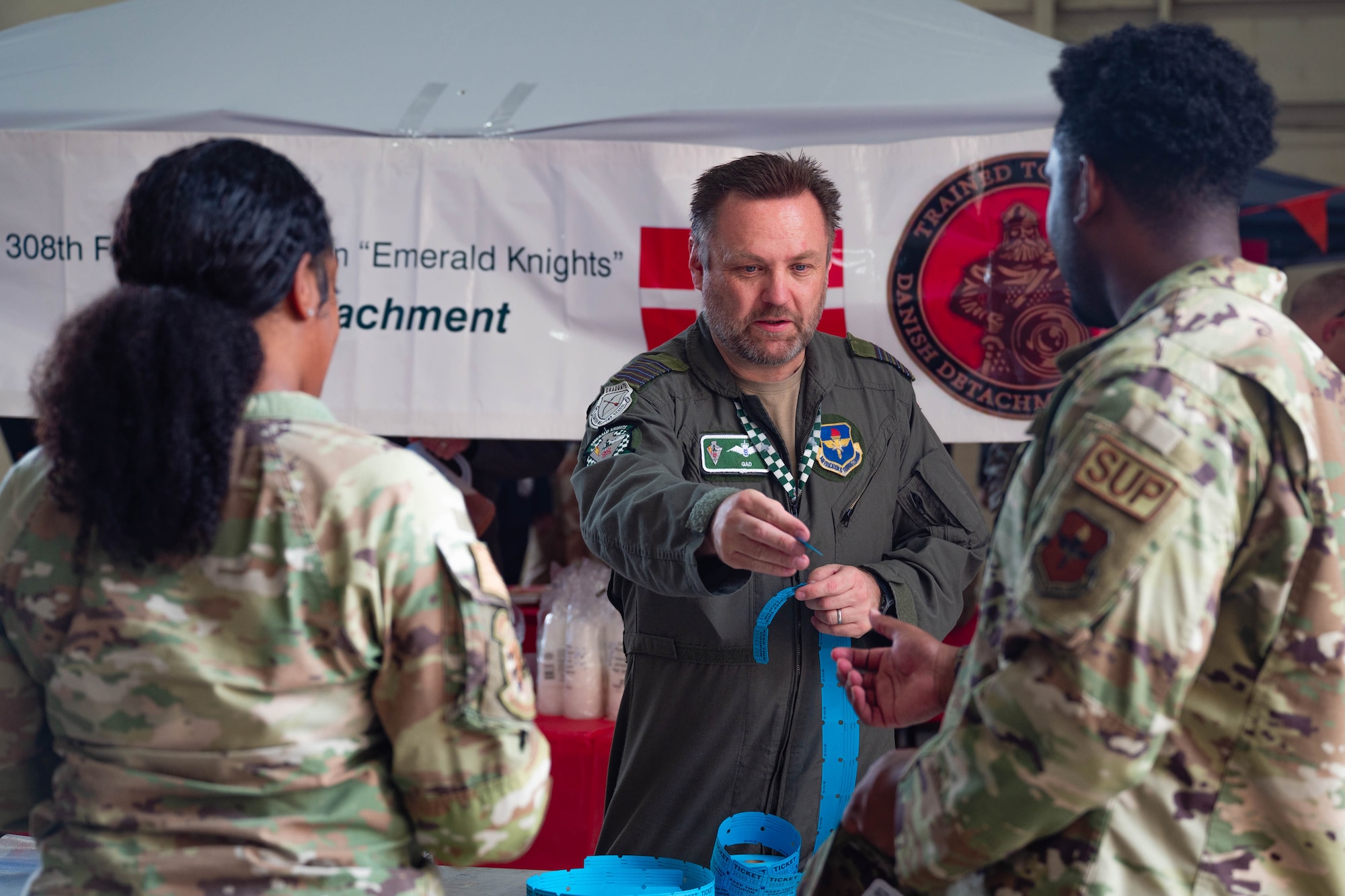 U.S. Air Force Airmen assigned to the 56th Fighter Wing receive raffle tickets from a Belgian pilot during International Day 2026, April 10, 2026, at Luke Air Force Base, Arizona.