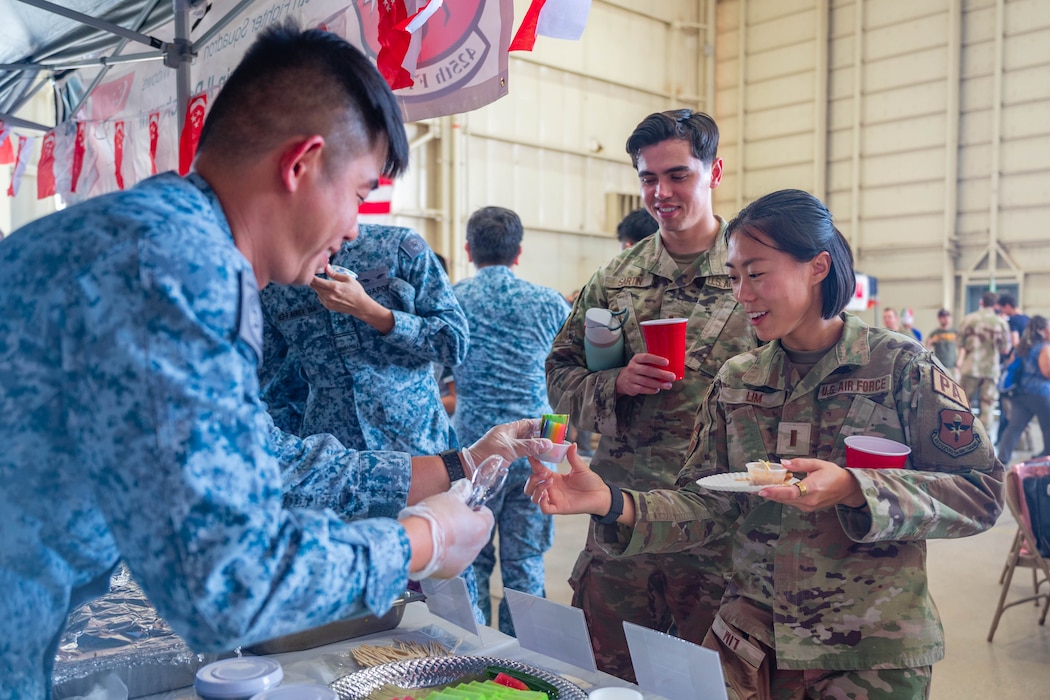 A Republic of Singapore service member hands pandan chiffon cake to U.S. Air Force Airmen assigned to the 56th Fighter Wing during International Day 2026, April 10, 2026, at Luke Air Force Base, Arizona.