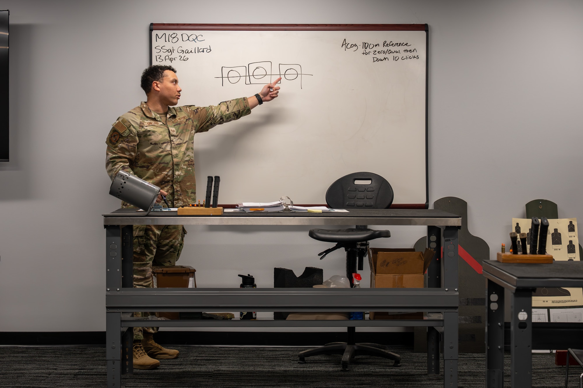 A uniformed man points at a white board.
