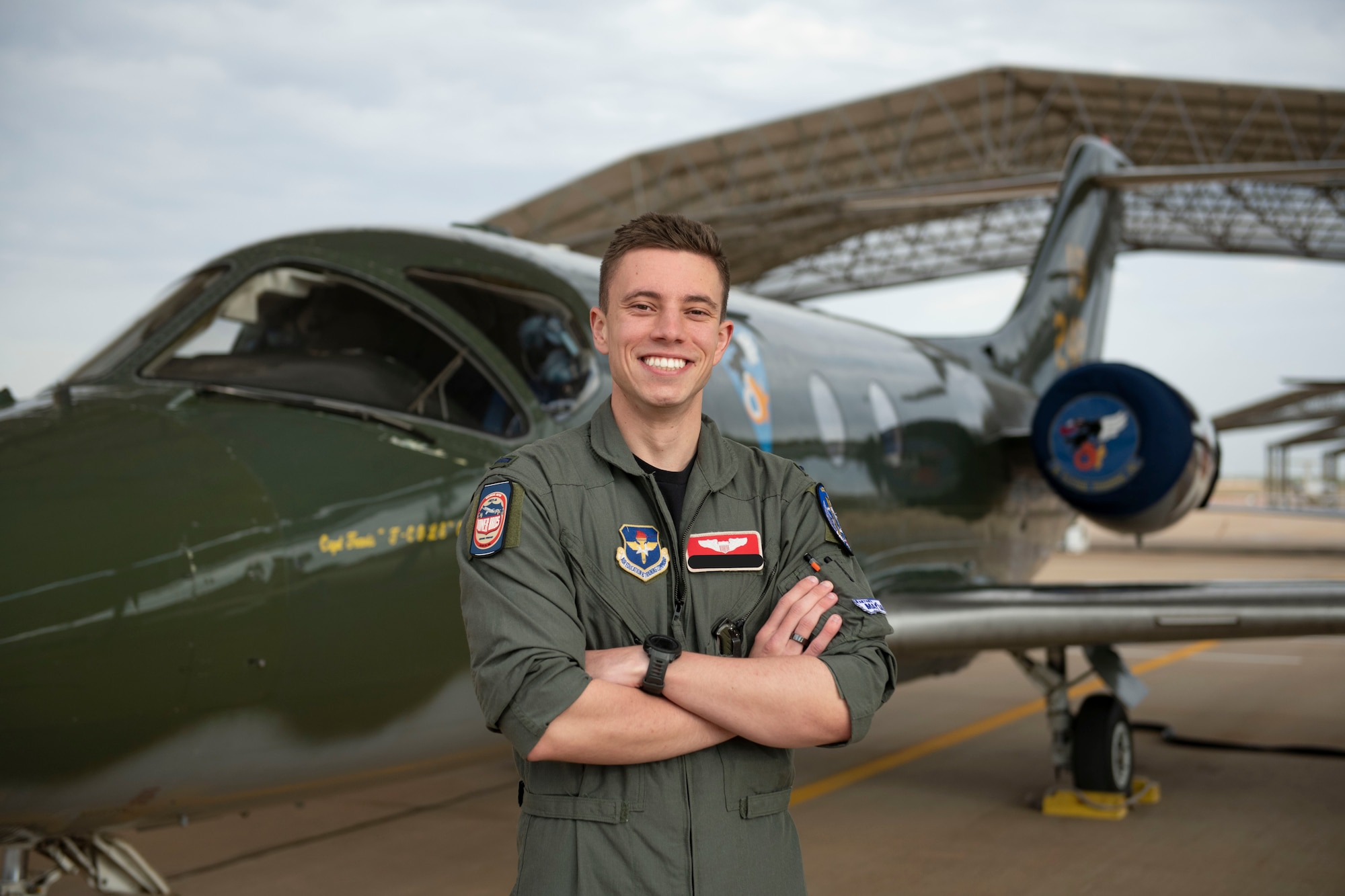 A military member poses in front of a plane.