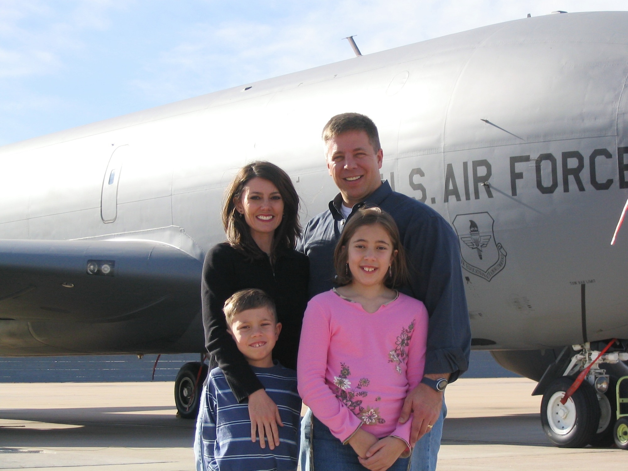 A family poses in front of an airplane