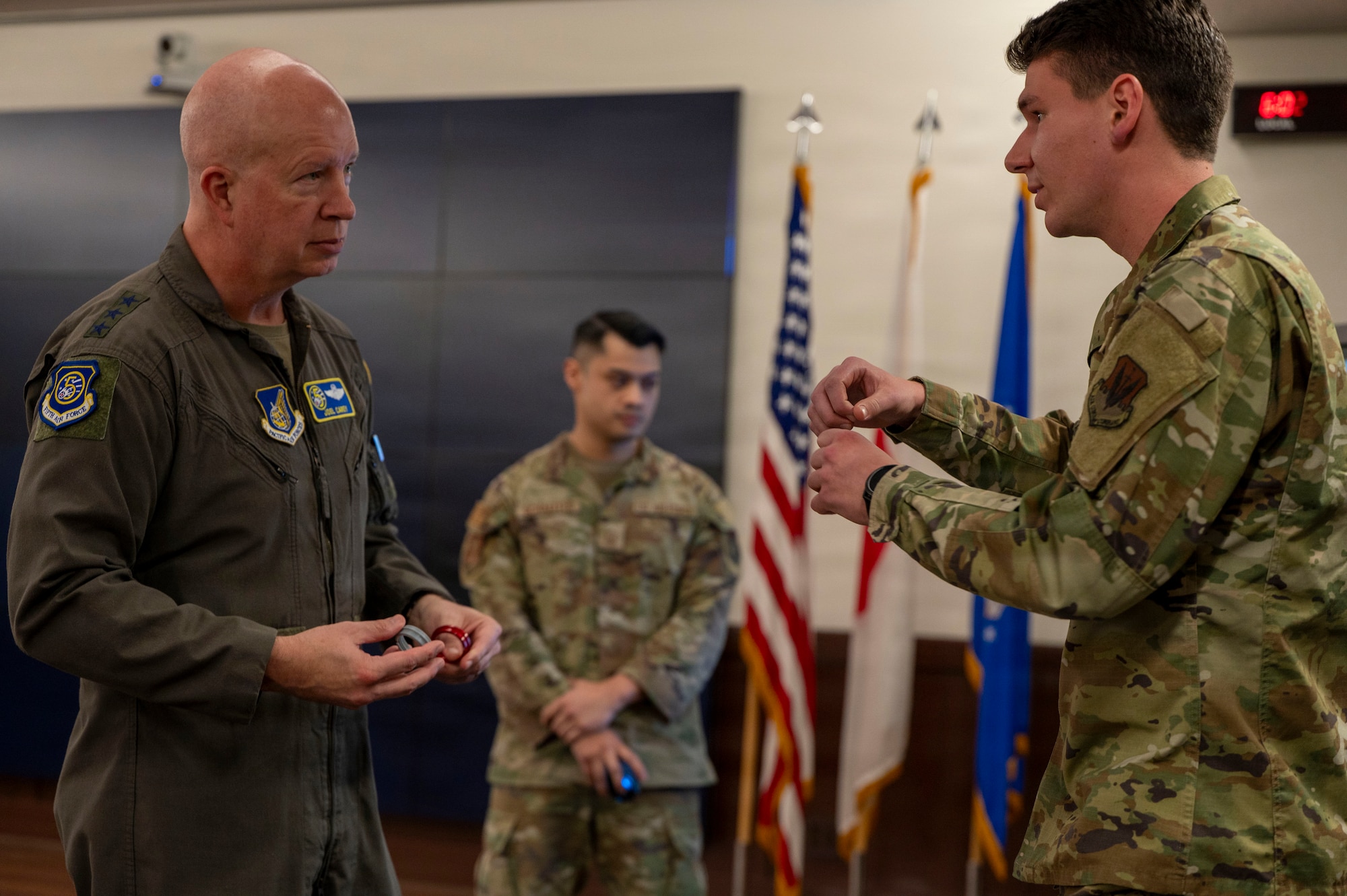U.S. Air Force Lt. Gen. Joel Carey, Fifth Air Force commander, holds a 3D-printed O-ring while speaking with 1st Lt. Thomas Wachter 49th Test and Evaluation Squadron operational test engineer.