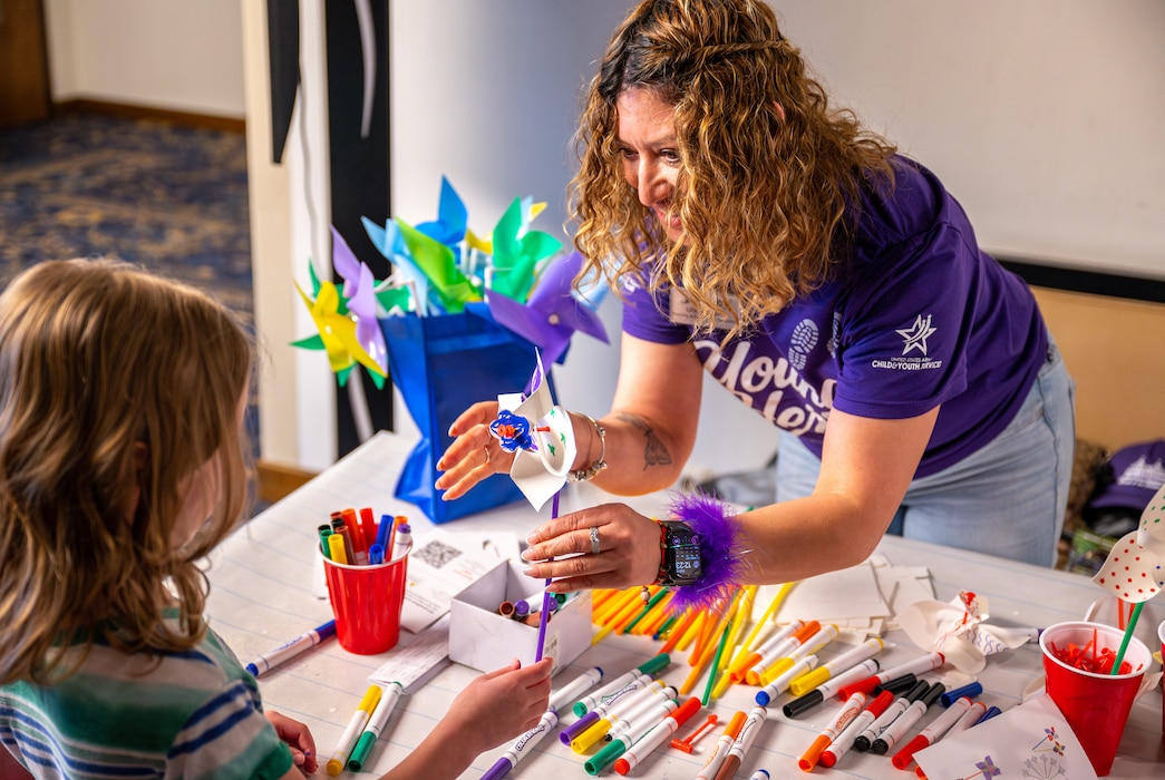 Liliana Kaiser, 86th Force Support Squadron child development center training and curriculum specialist, makes pinwheels for children during a Month of the Military Child event at Ramstein Air Base, Germany, April 12, 2026. The event brought together base agencies and volunteers to share resources and connect with military families. (U.S. Air Force photo by Senior Airman Jared Lovett)