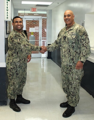DAHLGREN, Va. – Rear Adm. Reginal Ewing, III, director, Defense Health Agency-National Capital Region, presents a coin to Hospital Corpsman 2nd Class Morales recognizing him for maintaining the laboratory's high standards during a four-month gap without a laboratory officer. Despite having only five years of service, Morales has demonstrated a rare balance of knowledge, skill, and diligence, with a technical expertise that has been compared to that of a more senior technician.