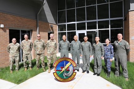 Group photo in front of the new Air Support Operations building during a visit to Camp Murray, Wash., April 13, 2026.