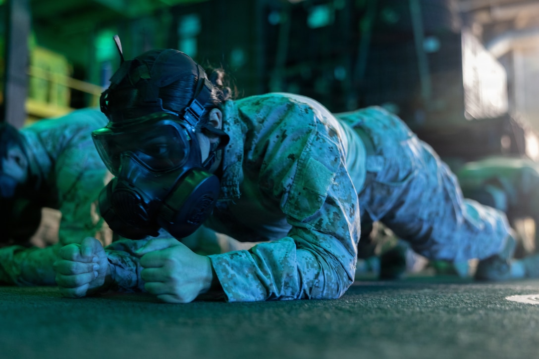 A U.S. Marine with Combat Logistics Battalion 26, 22nd Marine Expeditionary Unit (Special Operations Capable), conducts physical training in a gas mask during a Chemical, Biological, Radiological, and Nuclear defense drill aboard San Antonio-class amphibious transport dock USS San Antonio (LPD 17), while underway in the Caribbean Sea, April 3, 2026. U.S. military forces are deployed to the Caribbean in support of the U.S. Southern Command mission, Department of War-directed operations, and the president’s priorities to disrupt illicit drug trafficking and protect the homeland. (U.S. Marine Corps photo)