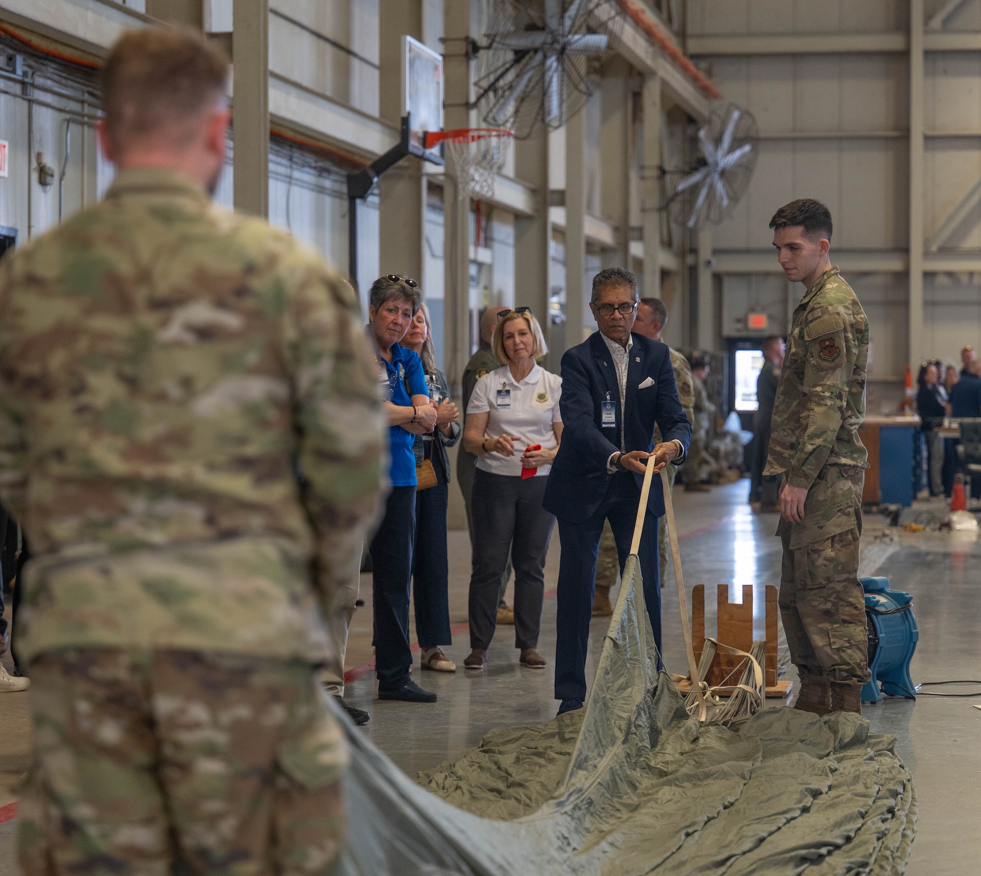 Jamil Dada, Air Mobility Command civic leader, takes part in an interactive parachute building demonstration at Altus Air Force Base, Oklahoma, April 9, 2026. The visit provided civic leaders the opportunity to engage with Airmen assigned to the 97th Logistics Readiness Squadron offering insight into how Airmen pack parachutes used for training purposes. (U.S. Air Force photo by Airman 1st Class Emma Wright)