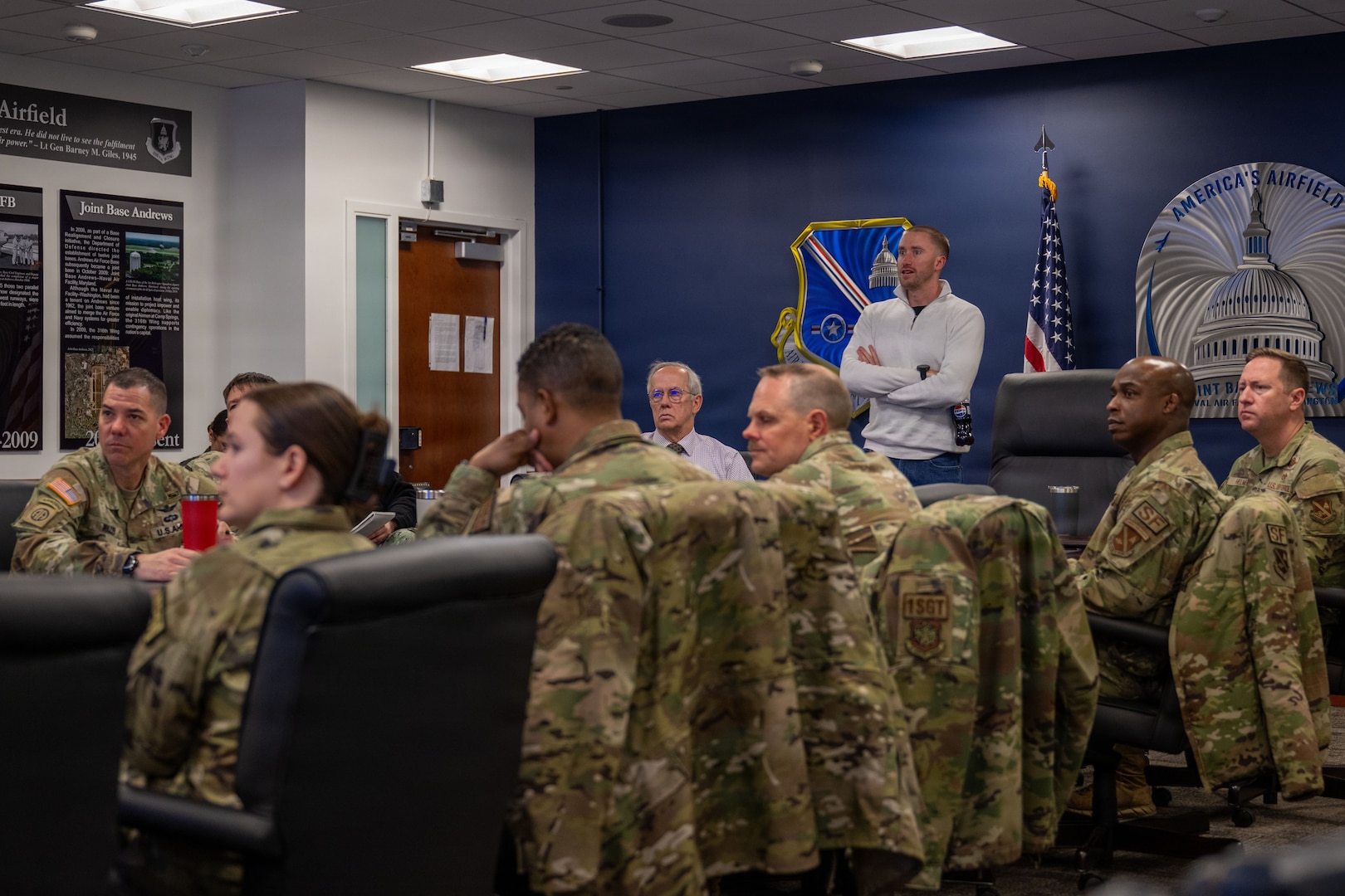Uniformed service members sitting around conference table.