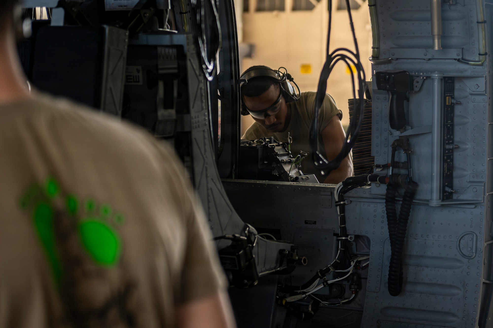 Airman preparing to put on an armament system onto a HH-60W Jolly Green II.