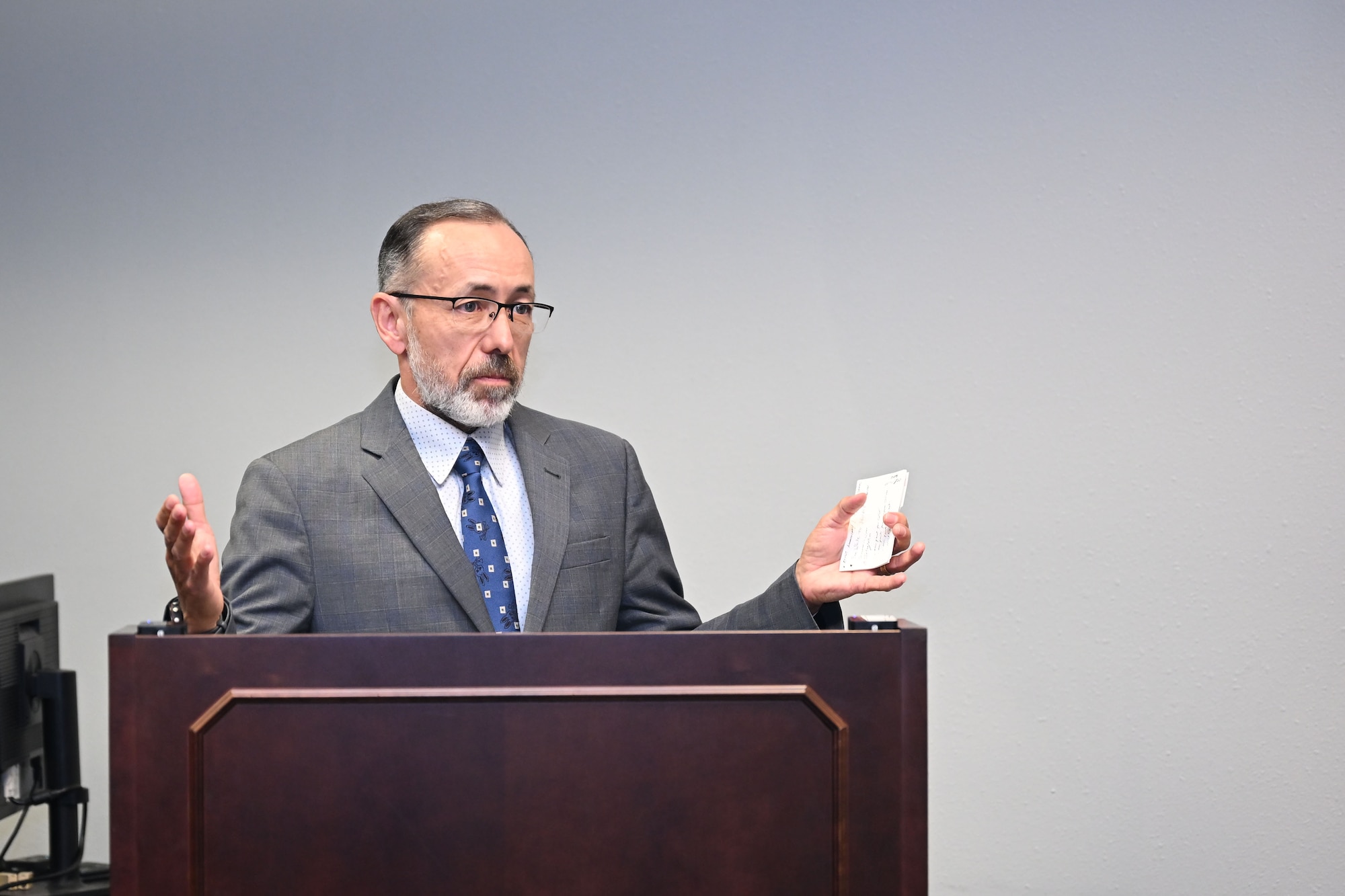 Man in suit speaks at podium while holding note cards