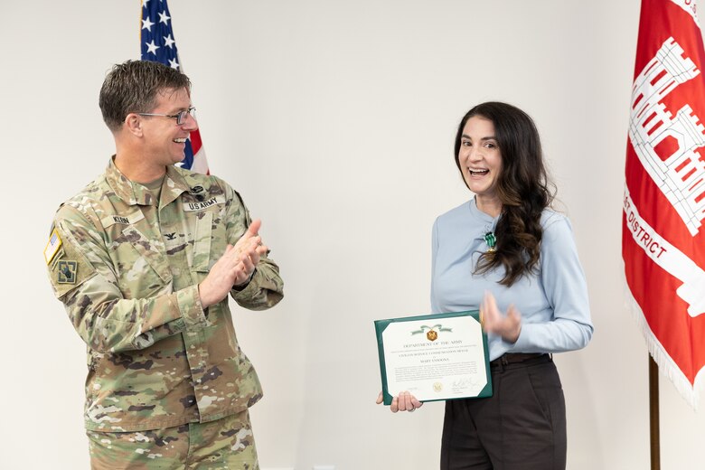 Man applauds near woman holding certificate