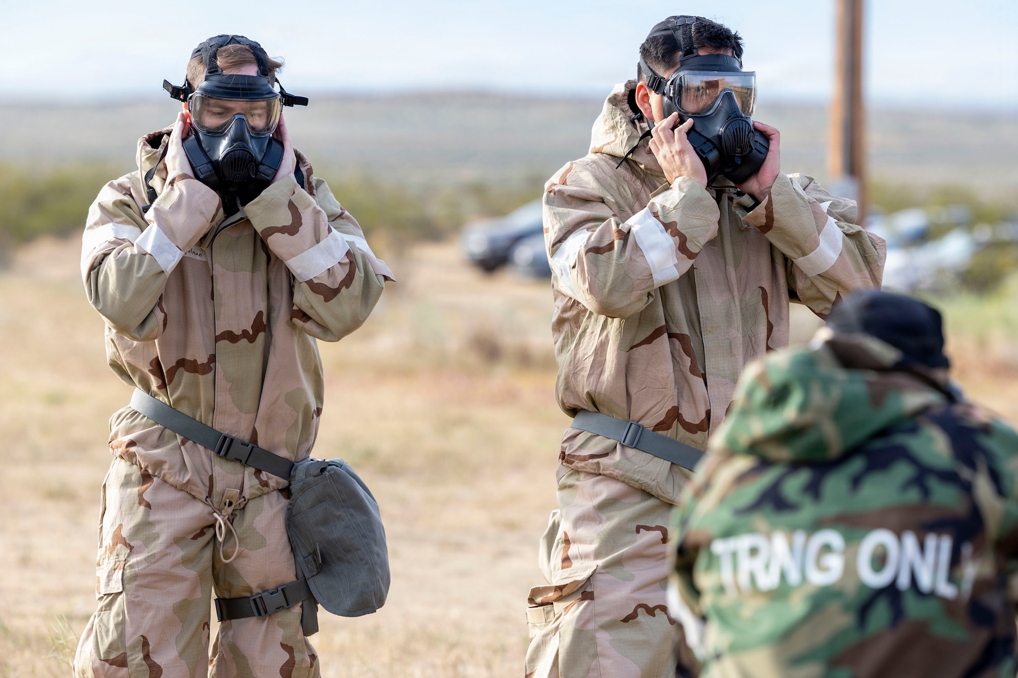 U.S. Air Force Staff Sgt. Owen Kappelman, left, crew chief, 412th Aircraft Maintenance Squadron, and Senior Airman Samuel Cardenas, force management supervisor, 412th Force Support Squadron, check mask seals as part of a chemical, biological, radiological, and nuclear threats defense exercise at Edwards Air Force Base, California, March 30, 2026. The validation exercise validated the Airmen's skills and knowledge in operating a CBRN-degraded environment. (U.S. Air Force photo by Jennifer Healy)