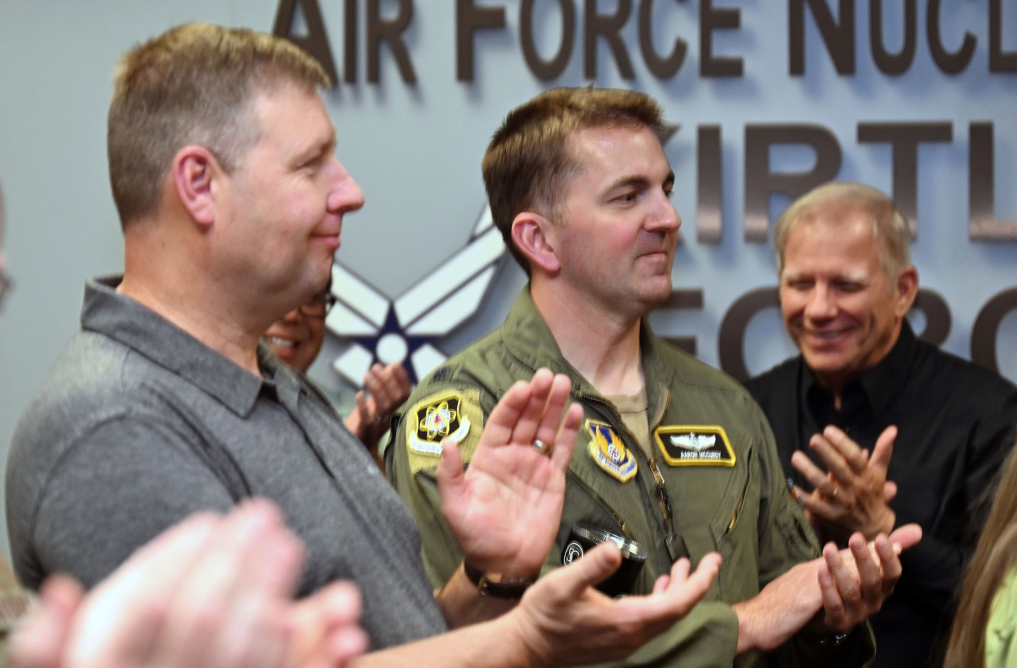 Several men, in uniform and civilian attire, clap