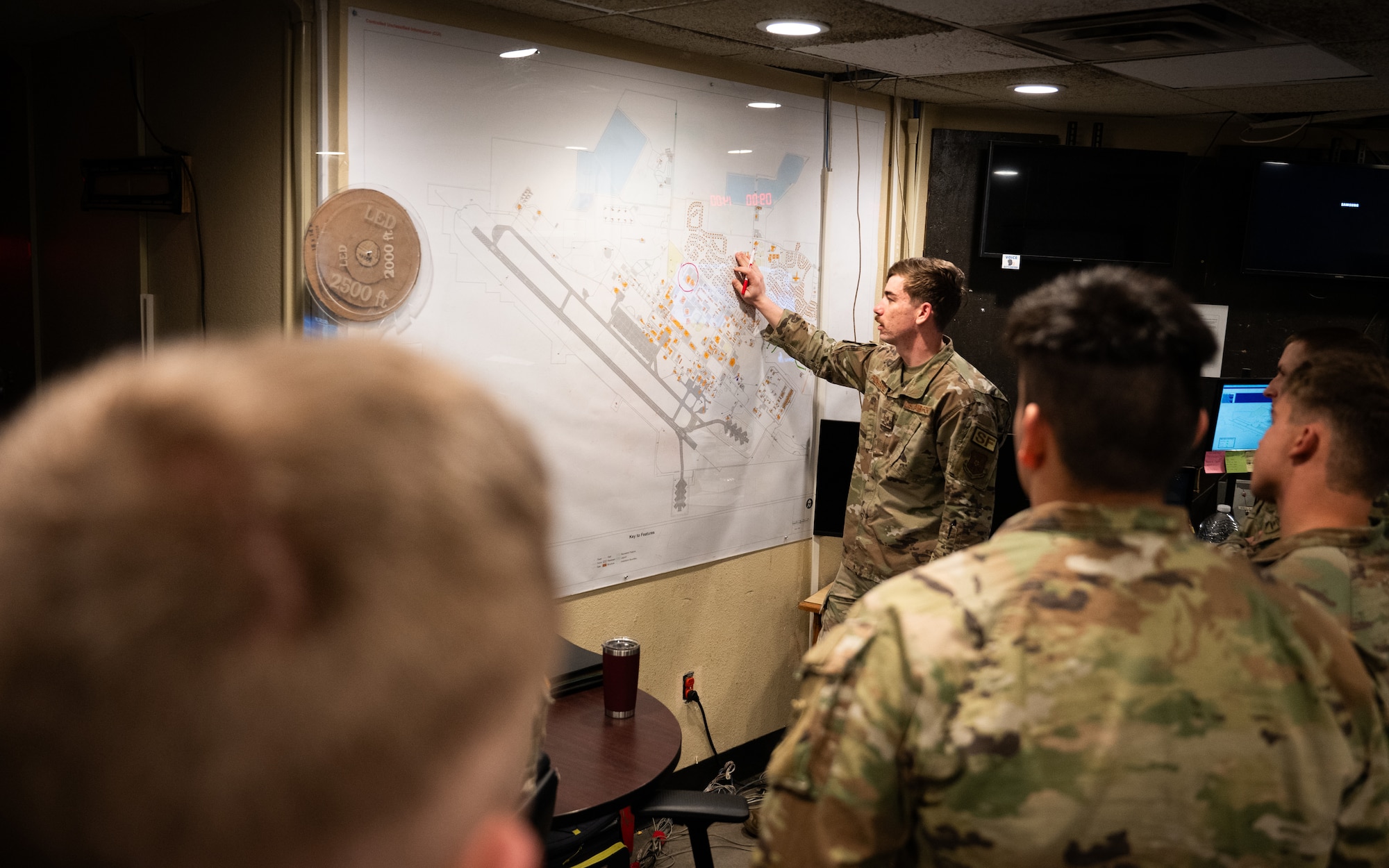 A U.S. Air Force defender briefs about base defense operations center procedures to U.S. Army soldiers.