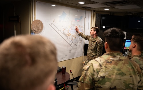 A U.S. Air Force defender briefs about base defense operations center procedures to U.S. Army soldiers.