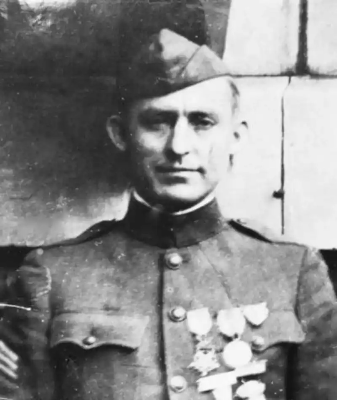 A man in a military dress uniform with medals on his left chest poses for a photo.