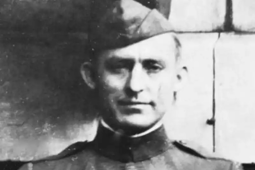 A man in a military dress uniform with medals on his left chest poses for a photo.