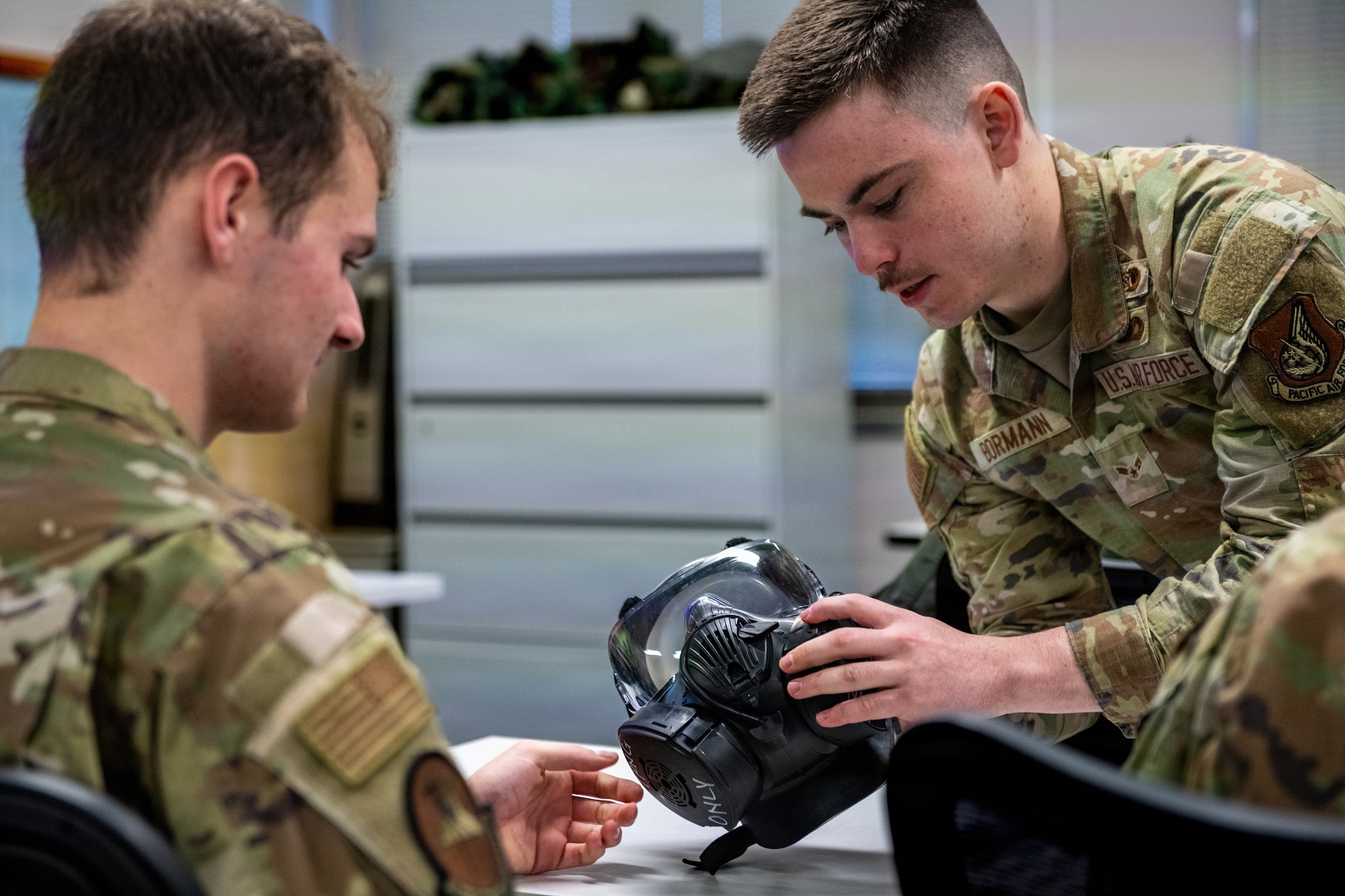U.S. Air Force Airman 1st Class Gabriel Bormann, 35th Civil Engineer Squadron emergency management journeyman, assists in removing the filters from a gas mask for Airman Ryan Dornberger, 35th Civil Engineer Squadron structural apprentice, during a chemical, biological, radiological and nuclear (CBRN) class.