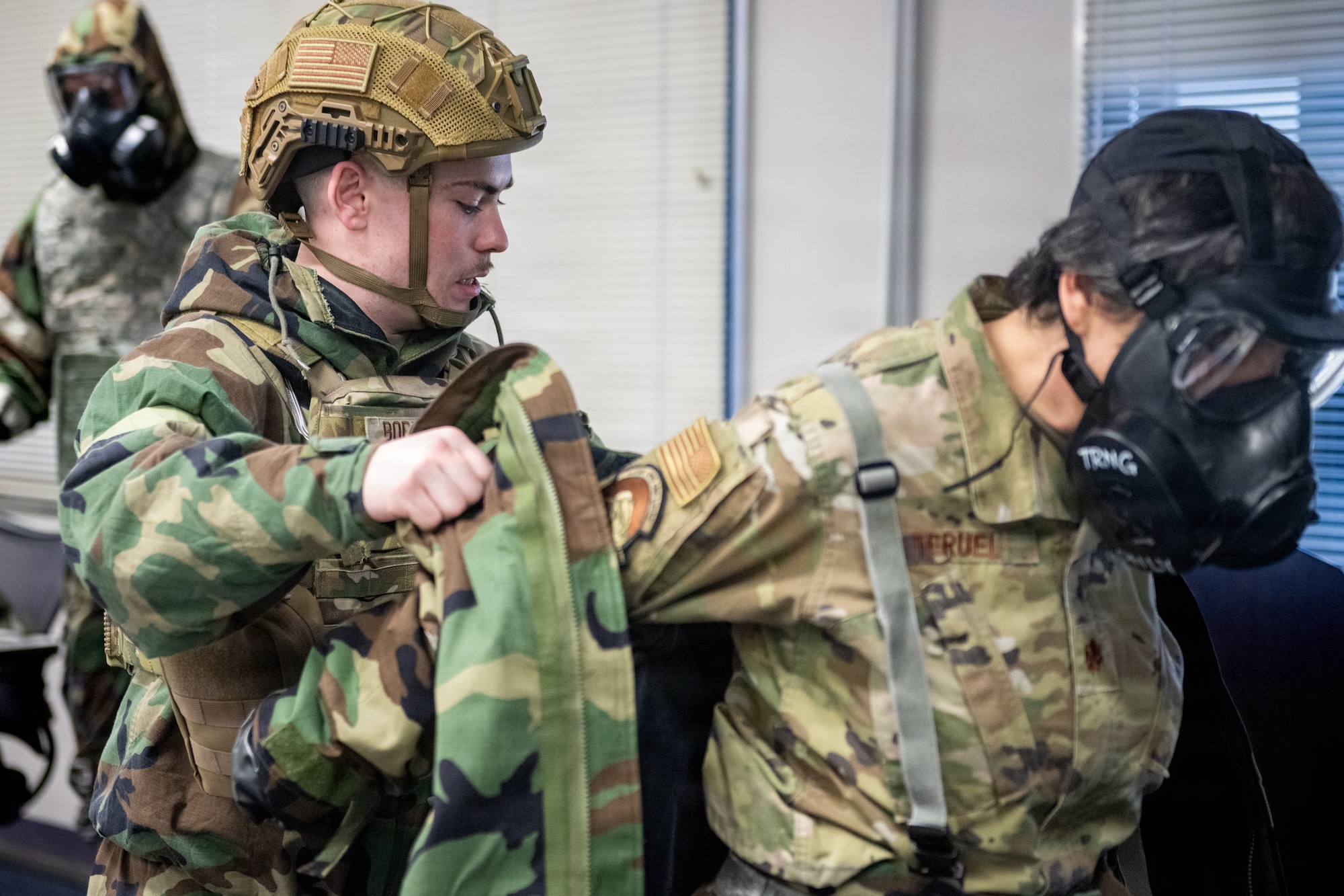 U.S. Air Force Maj. Claudia Teruel, right, 35th Surgical Operations Squadron element chief, and Airman 1st Class Gabriel Bormann, 35th Civil Engineering Squadron emergency management journeyman, demonstrate how to remove simulated contaminated gear during a chemical, biological, radiological and nuclear (CBRN) class.