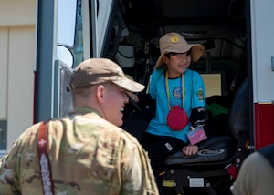 A child sits inside the front seat of a fire truck.