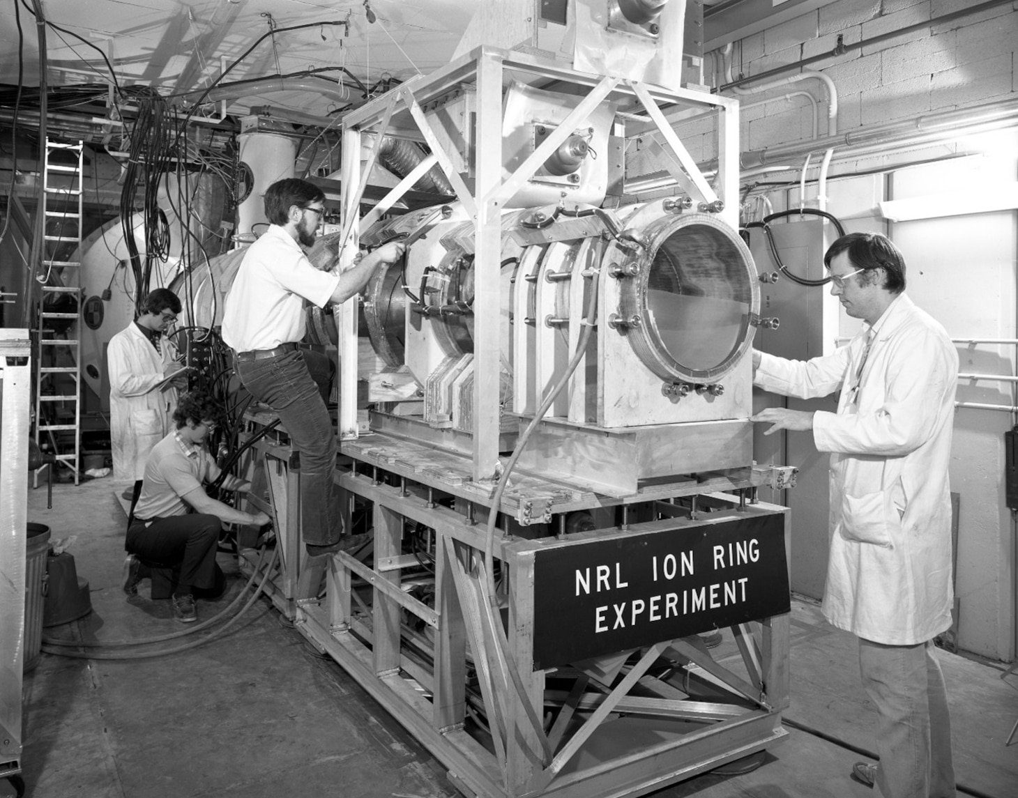 U.S. Naval Research Laboratory scientists work on the Ion Ring Experiment in this archival image of the Gamble II, a system used to study high-energy plasma behavior and confinement. The research contributed to advances in fusion science and high-energy density physics. (U.S. Navy photo)